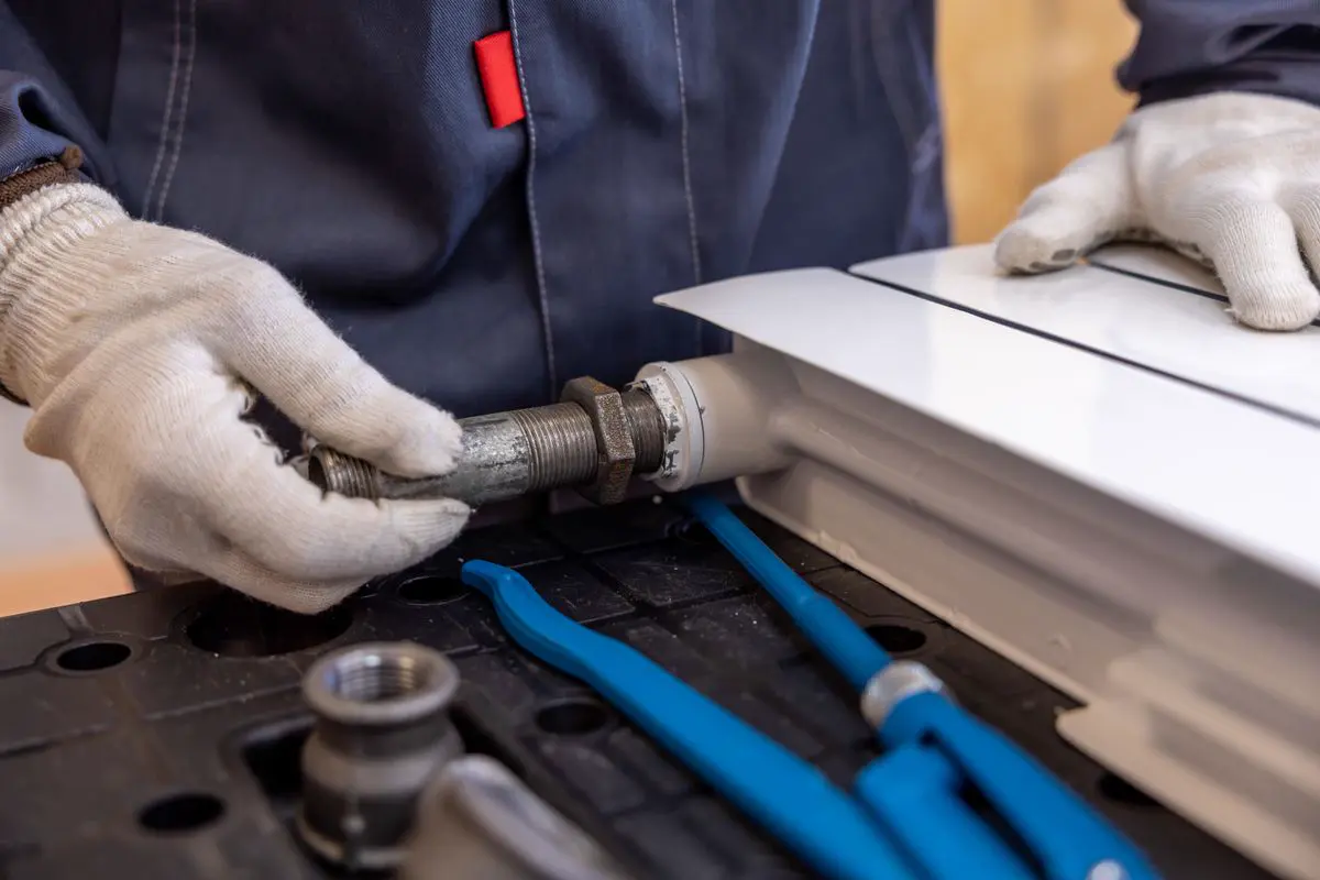 Free Close-up of a plumber installing a radiator pipe using specialized tools. Stock Photo