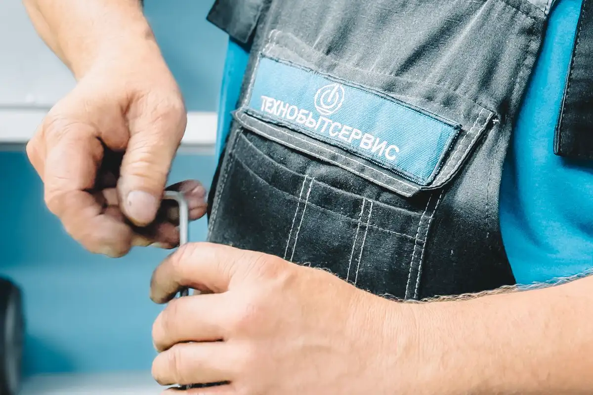Free Close-up of a plumber in blue uniform working on a pipe repair with a wrench. Stock Photo