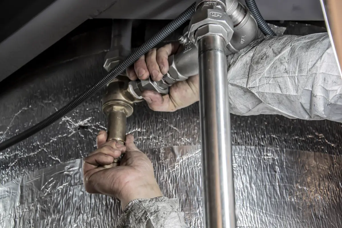 Free Close-up of a plumber's hands installing steel pipes indoors, showcasing skilled manual work. Stock Photo