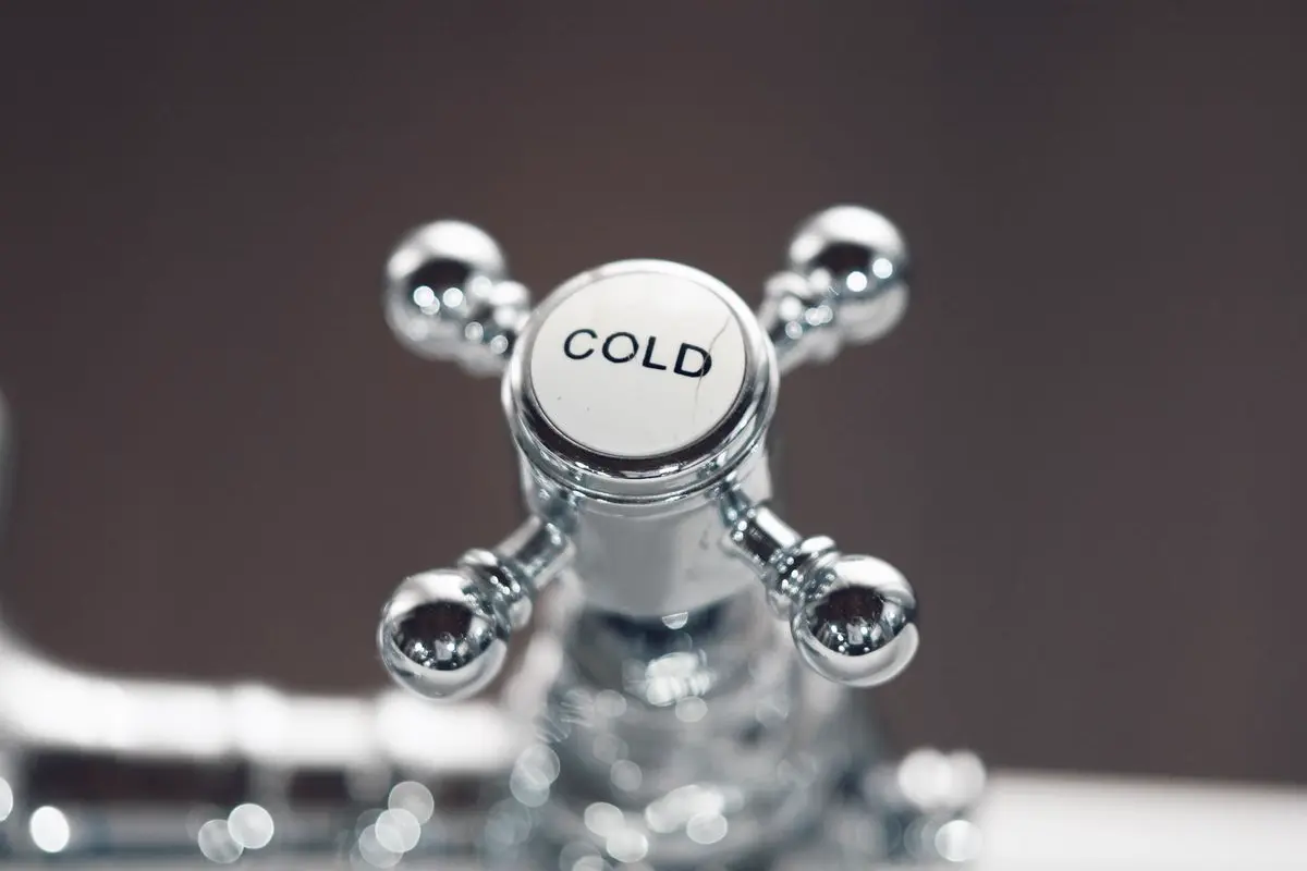 Free Elegant close-up of a chrome bathroom faucet with a cold water handle, offering a modern touch. Stock Photo