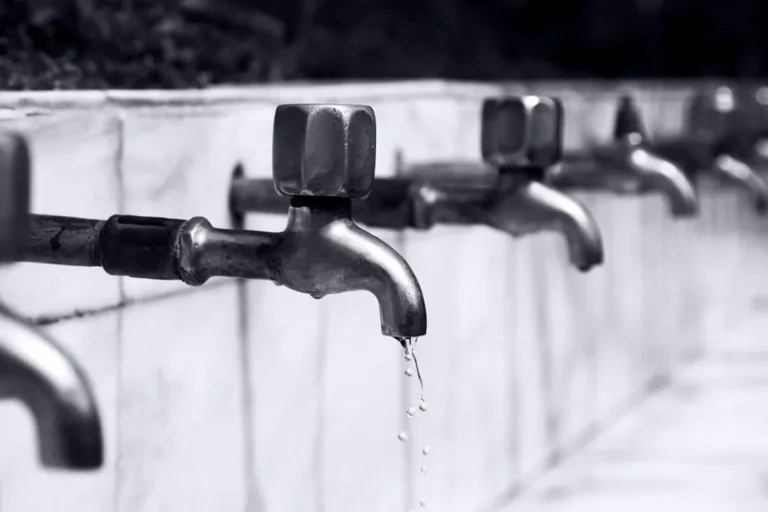 Free Black and white image of a row of faucets with water dripping, highlighting plumbing details. Stock Photo