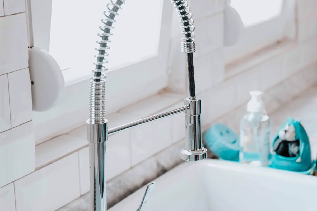 Chrome spring-coil pull-down kitchen faucet by a bright window