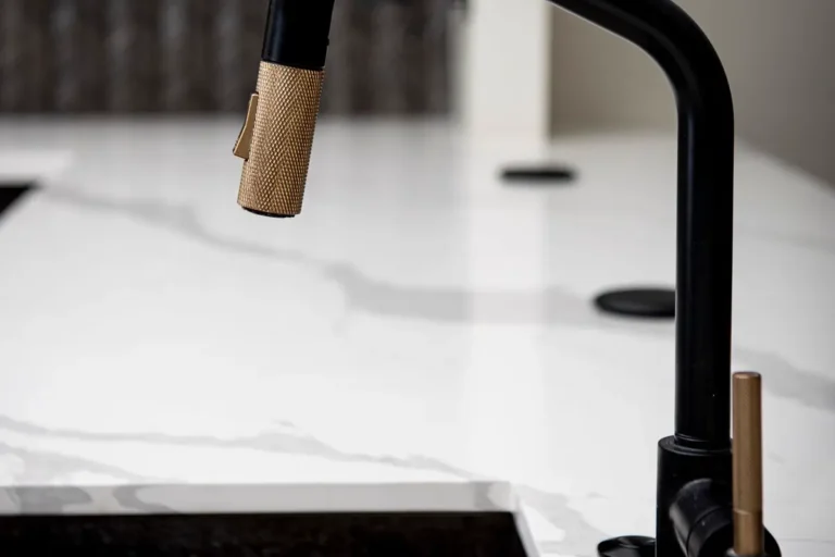 Modern black and brass pull-down kitchen sink faucet over a marble counter
