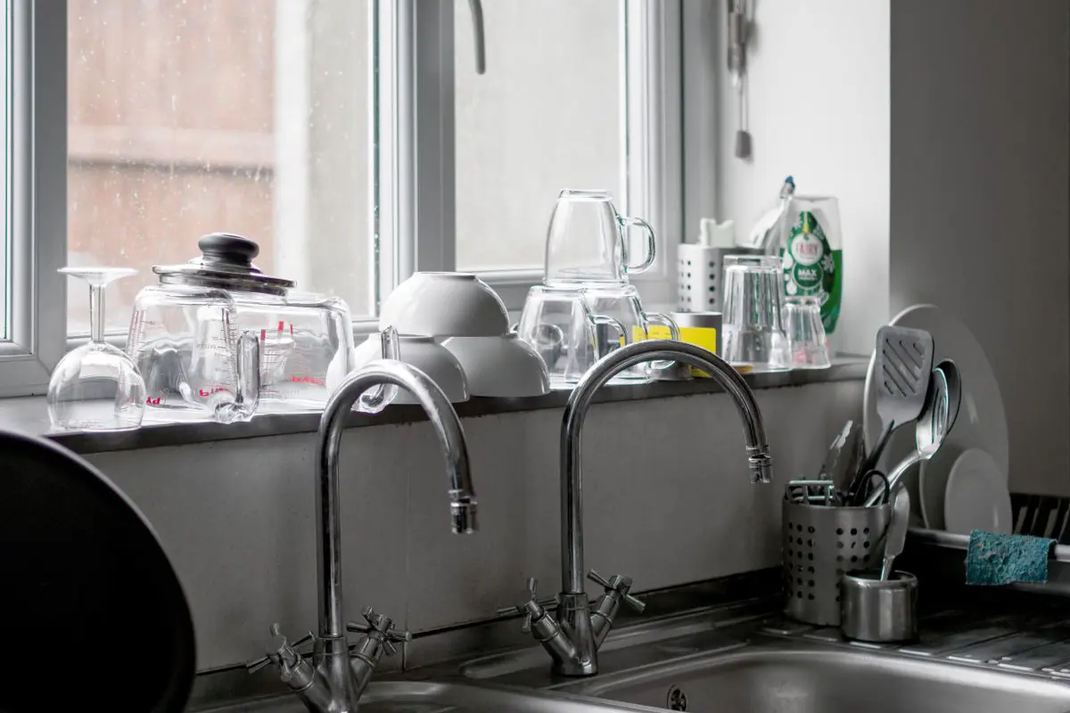 Double kitchen sink with chrome faucets and clean dishes by the window