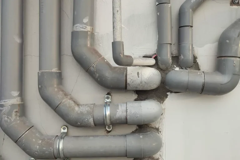 Free Close-up of interconnected gray metal pipes on an outdoor wall showcasing industrial design. Stock Photo