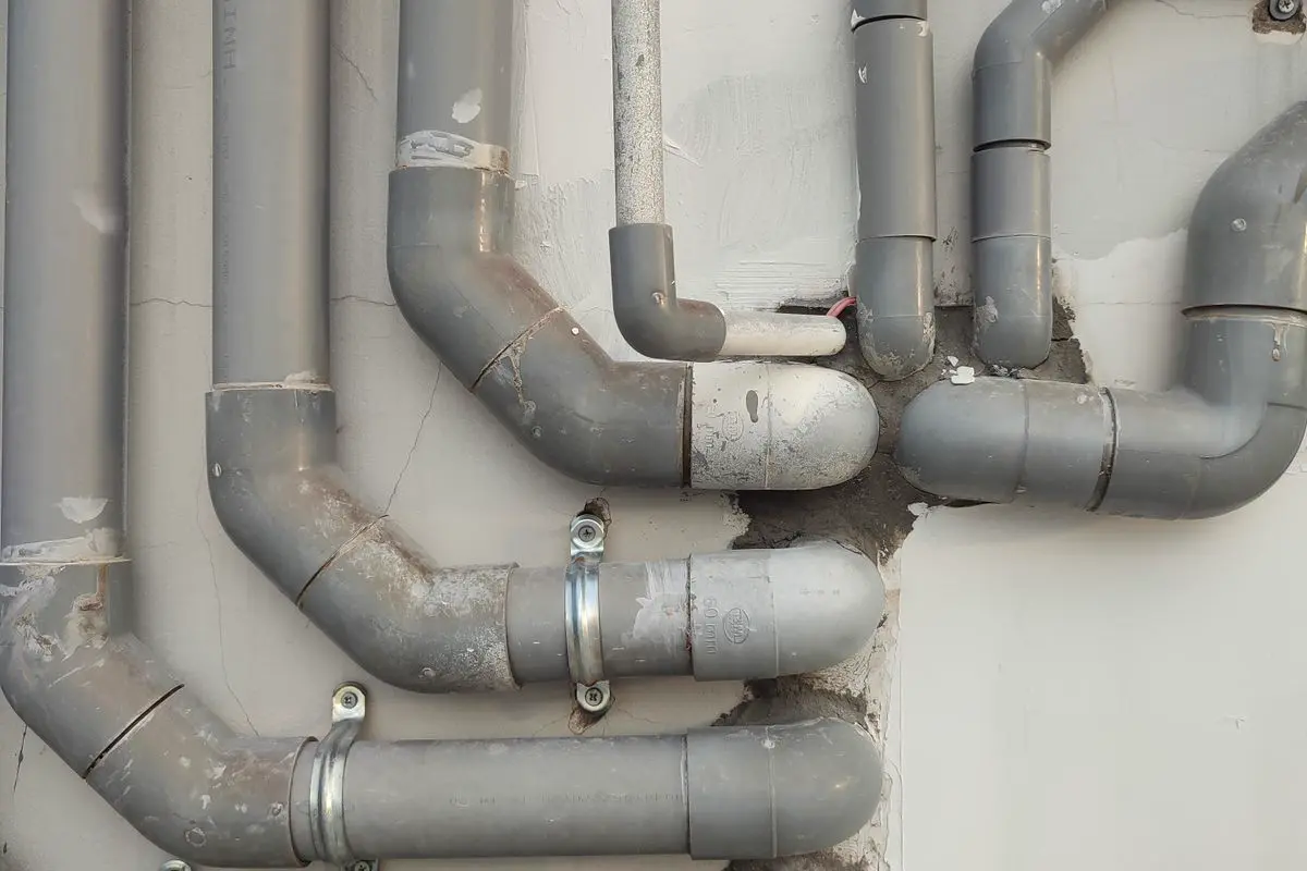 Free Close-up of interconnected gray metal pipes on an outdoor wall showcasing industrial design. Stock Photo