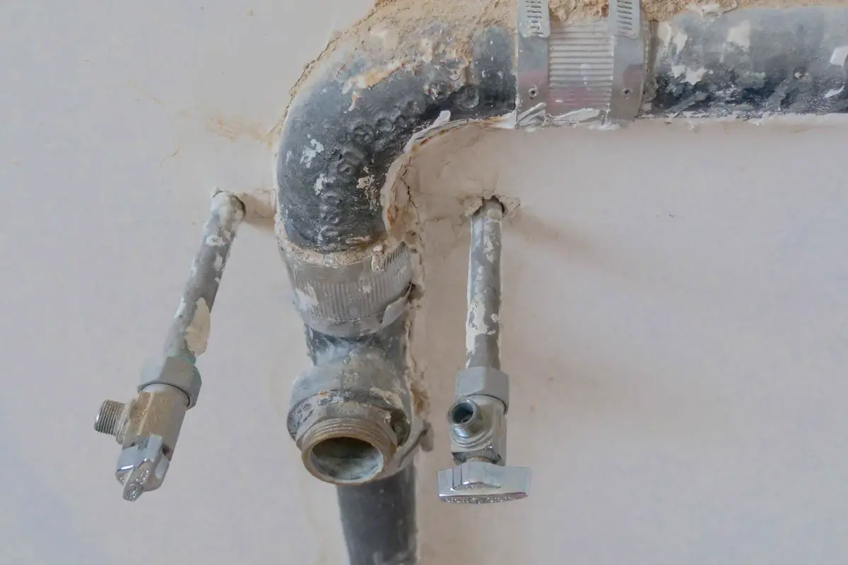 Free Close-up of exposed plumbing pipes with rustic textures on a construction site wall. Stock Photo