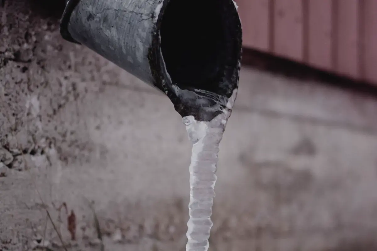 Free Frozen drain spout with icicle against a snowy backdrop. Captured in Estonia. Stock Photo