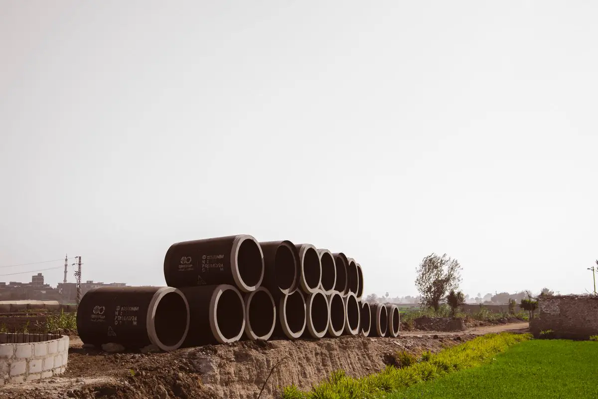 Free Large concrete pipes stacked in a rural landscape, ready for construction or drainage. Stock Photo