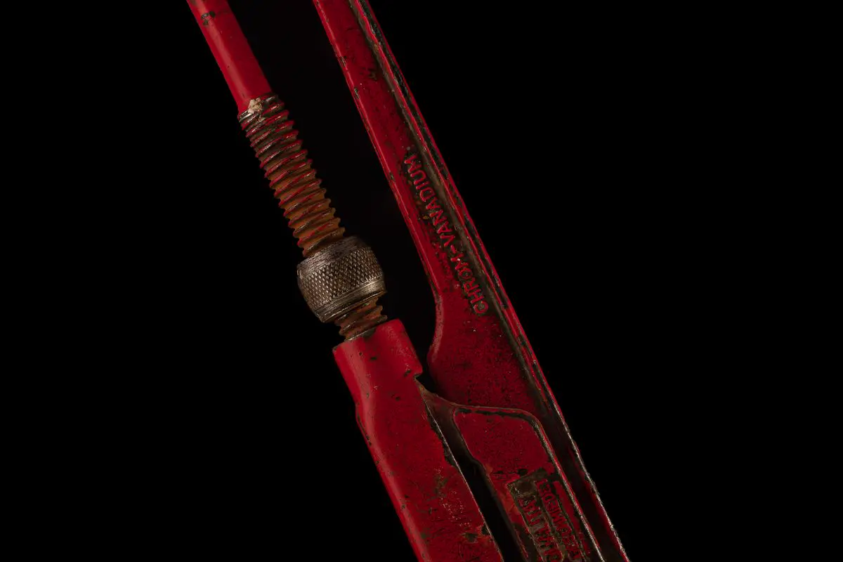 Free Red vintage pipe wrench isolated on black, showcasing rustic industrial charm. Stock Photo
