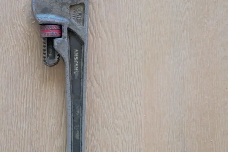Free Close-up of a metal plumber's wrench against a wooden surface, showcasing tool detail. Stock Photo