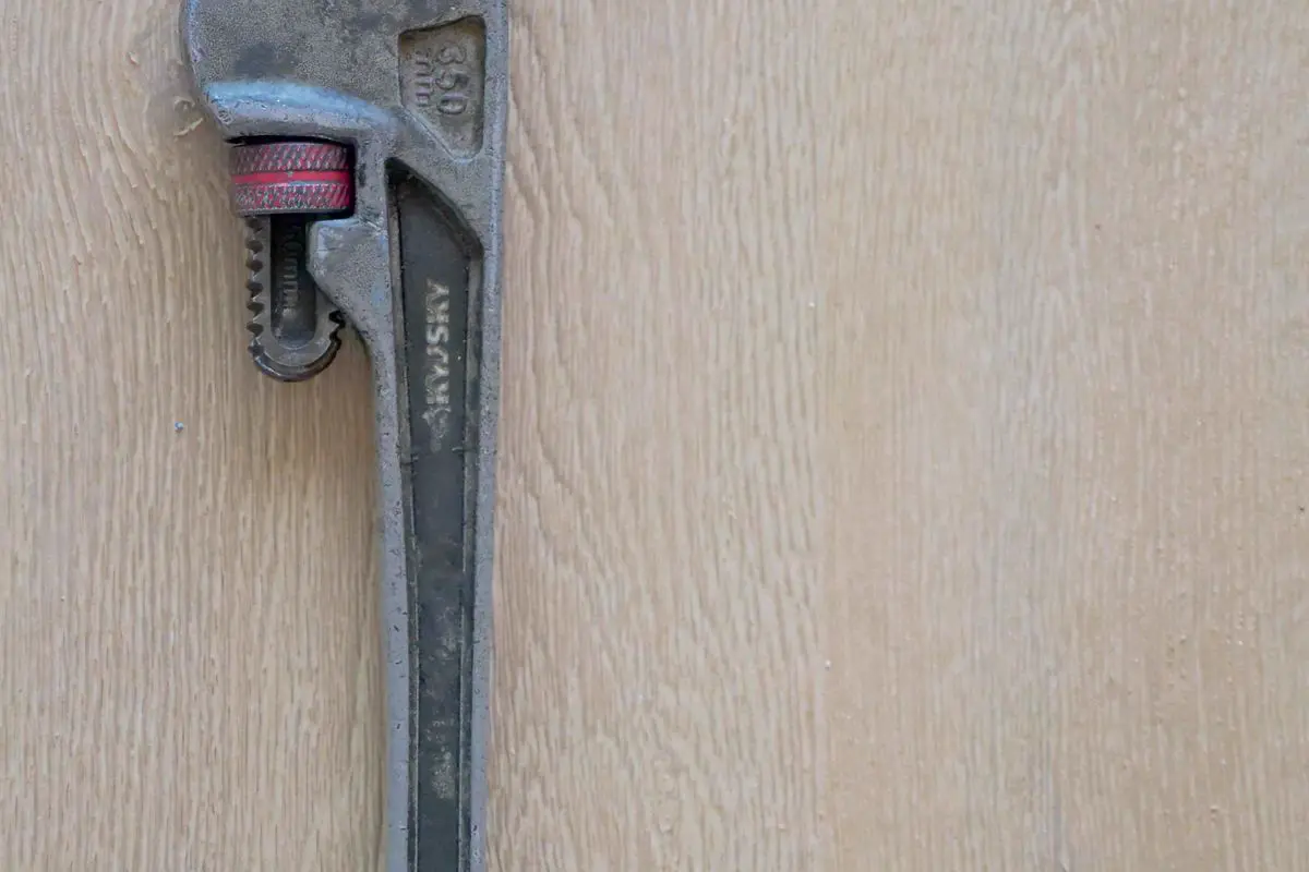 Free Close-up of a metal plumber's wrench against a wooden surface, showcasing tool detail. Stock Photo