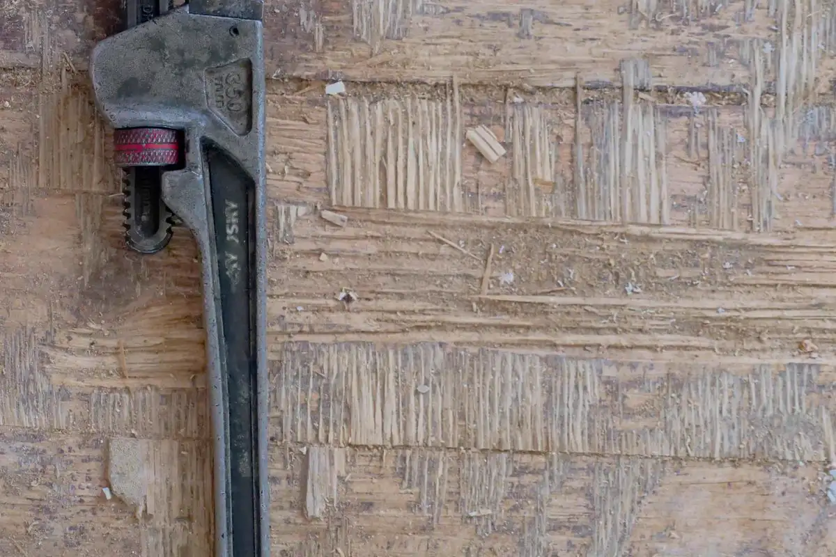 Free A vintage pipe wrench lays on a rustic wooden background, ideal for tool-themed projects. Stock Photo