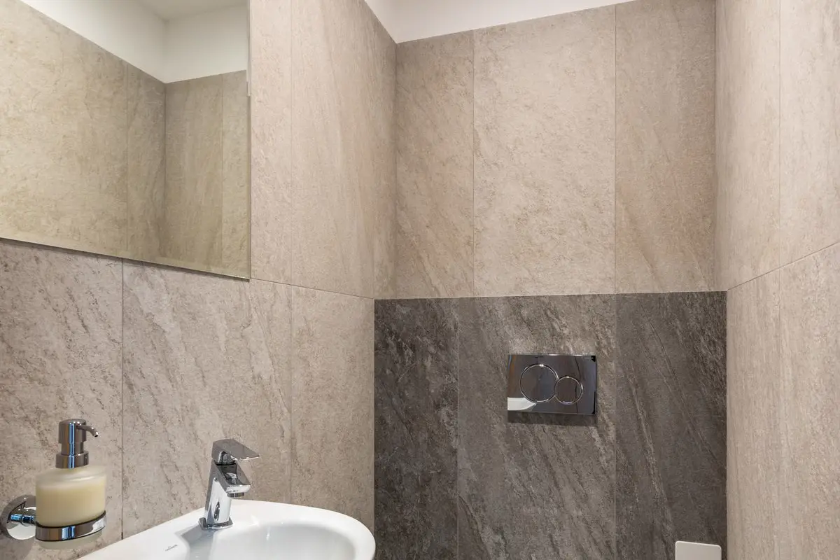 Free White ceramic sink and toilet bowl in modern bathroom with tiled walls and mirror Stock Photo